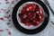 Beautiful garnet is divided into pieces in a black-and-white plate on gray background with fork closeup