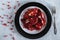 Beautiful garnet is divided into pieces in a black-and-white plate on gray background with fork closeup