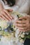 A beautiful gentle beige manicure of the elegance bride in her arms. Hands on a white wedding bouquet