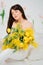 beautiful gentle young woman brunette with a bouquet of yellow tulips and mimosa