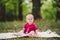Beautiful Girl 1 Years Old Sitting On The Plaid In The Park. Child outdoor. Baby at picnic in forest. Portrait of a beautiful baby