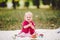 Beautiful Girl 1 Years Old Sitting On The Plaid In The Park. Child outdoor. Baby at picnic in forest. Portrait of a beautiful baby