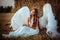 Beautiful girl with angel wings is sitting front of the hay