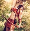 Beautiful girl archer with long blond hair with a bow and arrows dressed in leather