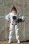 Beautiful girl astronaut without a helmet on the background of a gray wall. Fantastic space suit