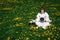 Beautiful girl astronaut without a helmet sits on a green lawn among flowers in a meditative position