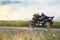 Beautiful girl biker lying on a motorcycle. She stopped on a road in a field.