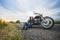 Beautiful girl biker sitting on the asphalt near her motorcycle. She stopped on a road between the fields.