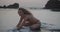 Beautiful girl in bikini on black beach at sunset