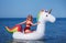 Beautiful girl in bikini swimming on giant unicorn during summer vacation