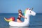 Beautiful girl in bikini swimming on giant unicorn during summer vacation