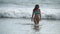 Beautiful girl in bikini walks out from ocean after swimming to the tropical beach. Young woman in swimsuit goes out