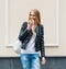 Beautiful girl bites a delicious donut walking on the streets of European city. Warm spring. Outdoor