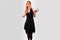 Beautiful girl in a black dress back dancing, on a gray background