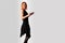 Beautiful girl in a black dress back dancing, on a gray background