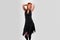 Beautiful girl in a black dress back dancing, on a gray background