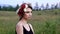 Beautiful girl in the black short dress with the wreath on her head on the green field.