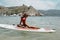 Beautiful girl with blond hair in elegant swimming suit  and accessories posing on the summer beach with surf board