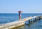 A beautiful girl in a blue bikini walks the pier to the sea. Marine concrete pier. Jumping into the water from the pier