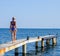 A beautiful girl in a blue bikini walks the pier to the sea. Marine concrete pier. Jumping into the water from the pier