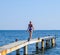 A beautiful girl in a blue bikini walks the pier to the sea. Marine concrete pier. Jumping into the water from the pier