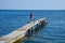 A beautiful girl in a blue bikini walks the pier to the sea. Marine concrete pier. Jumping into the water from the pier