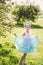 Beautiful girl in a blue dress in a green garden park smiling sunny day celebrates Halloween with unicorn