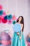 Beautiful girl in blue dress hold in hand huge candy in studio with decor of macaroons. Copy space.