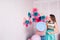 Beautiful girl in blue dress hold in hand huge candy in studio with decor of macaroons. Copy space.