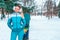 Beautiful girl in a blue jumpsuit on the background of a winter park and snowboard. Free space for text. Rest at resort