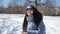 Beautiful girl in blue mirrored sunglasses and straight dark hair throwing snowballs playing with somebody outdoors in