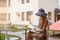 Beautiful girl in a blue straw hat and a summer dress sits at a cafe table and reads a book