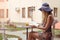 Beautiful girl in a blue straw hat and a summer dress sits at a cafe table and reads a book