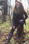 Beautiful girl in boots and jacket poses on tree stump