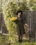 Beautiful girl with a bouquet of yellow roses. Woman with model appearance in a hat. Pretty woman near a vintage fence. Teenager