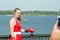 A beautiful girl in boxing gloves with medals being photographed against the background of a river on a hot summer day
