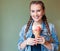 Beautiful girl with braids sitting in a cafe. She holds a huge multi-colored ice cream in waffle cone