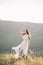 Beautiful girl bride in a long dress, winding in the wind hair decoration is in profile, outdoors, mountain, deer skull with