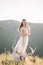 Beautiful girl bride in a long dress, winding in the wind hair decoration is in profile, outdoors, mountain, deer skull with