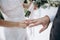 Beautiful girl bride in wedding white dress puts on the groom`s finger the wedding gold ring