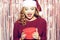 Beautiful girl in a bright santa hat is holding a red box with a gift for the new year. Christmas brunette in a red sweater
