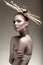 Beautiful girl with a bronze skin, pale makeup and unusual accessories. Art beauty image. Beauty face.