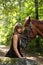 Beautiful girl and brown horse portrait in mysterious forest