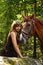Beautiful girl and brown horse portrait in mysterious forest