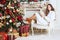 Beautiful girl in the chair near the Christmas tree and fireplace. New Year, toned image, the author`s processing