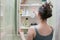 Beautiful girl choosing beauty products from the bathroom shelf and take it