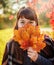 Beautiful girl closes face a bouquet of autumn maple leaves