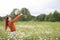 Beautiful girl collects daisies in summer field