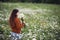 Beautiful girl collects daisies in summer field