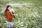 Beautiful girl collects daisies in summer field
